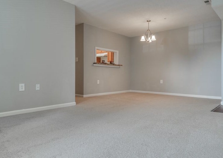 Empty living room and dining with carpet and dining chandler